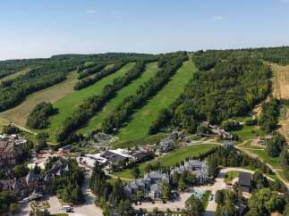 Experience the ultimate mountain getaway with this stunning aerial view of a resort nestled amidst lush green hills.