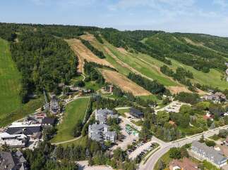 Experience the ultimate mountain getaway with this stunning aerial view of a ski resort and surrounding residential area.