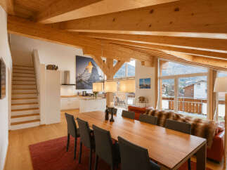 Experience luxury mountain living in this stunning chalet featuring a spacious open-plan living, dining, and kitchen area with exposed wooden beams and breathtaking panoramic views.