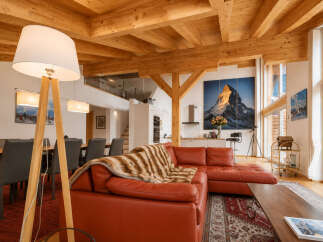 Experience luxurious alpine living in this stunning open-concept living space, featuring exposed wooden beams and a grand fireplace.