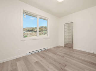 Discover modern living in this bright and airy room featuring a large window with scenic views and a sleek baseboard heater.