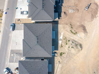 Discover modern living in this newly constructed home, featuring a sleek dark roof and spacious driveway.