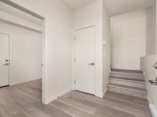 Step into this modern entryway featuring sleek laminate flooring and crisp white doors.