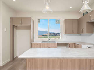 Experience modern living in this stunning kitchen featuring sleek, taupe cabinetry and a spacious island with a light-toned countertop.