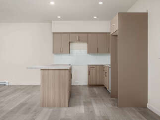 Discover modern living in this spacious kitchen featuring sleek, taupe cabinetry and a convenient island with a stone countertop.