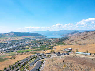 Discover breathtaking panoramic views from this elevated property, showcasing a serene lake and rolling hills.