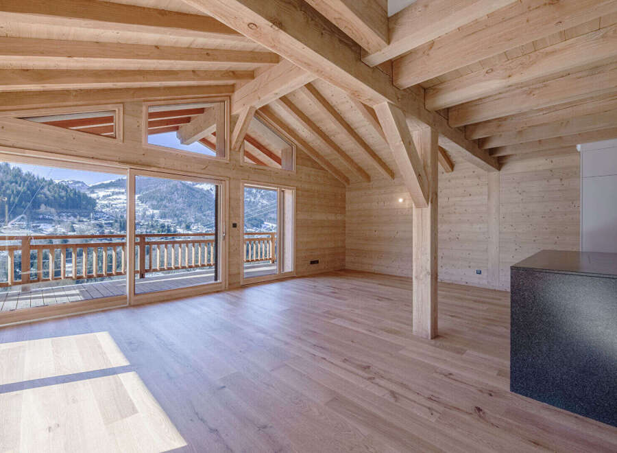 Experience luxurious mountain living in this stunning wooden chalet, featuring expansive glass doors that open to breathtaking panoramic views of snow-capped peaks and a charming village.
