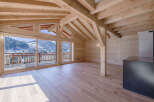 Experience luxurious mountain living in this stunning wooden chalet, featuring expansive glass doors that open to breathtaking panoramic views of snow-capped peaks and a charming village.