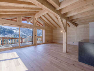 Experience luxurious mountain living in this stunning wooden chalet, featuring expansive glass doors that open to breathtaking panoramic views of snow-capped peaks and a charming village.