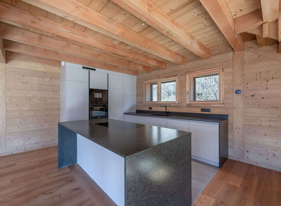 Experience modern living in this stunning kitchen featuring a sleek, dark granite island with an integrated stovetop, perfect for culinary enthusiasts.