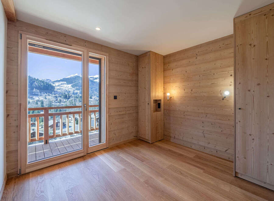 Experience breathtaking mountain views from this charming room featuring natural wood paneling and a spacious balcony.