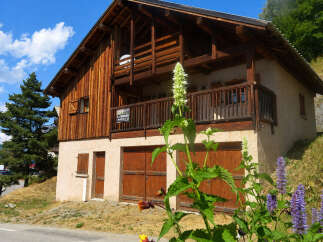 Charming wooden chalet with a rustic facade, featuring a spacious balcony and double garage doors.