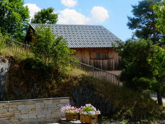 Discover this charming wooden house nestled on a hillside, offering a rustic retreat with a modern metal roof.