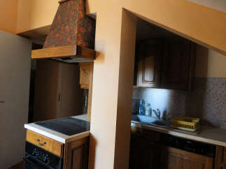 This kitchen features a unique, decorative range hood above a modern stovetop and oven.
