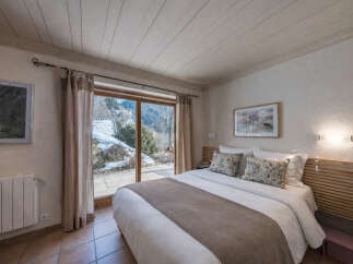 Experience serene mountain living in this charming bedroom, featuring a cozy bed with plush pillows and a warm throw.