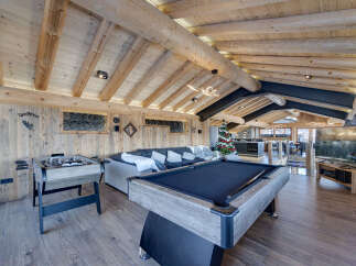 Experience luxury mountain living in this stunning chalet, featuring a spacious entertainment area with a pool table and foosball.