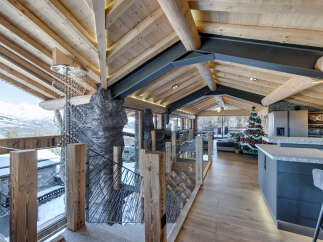 Experience luxury mountain living in this stunning chalet, featuring a unique open-plan design with exposed wooden beams and a dramatic stone fireplace.