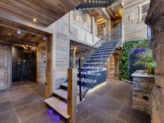 Experience luxury mountain living in this stunning chalet featuring a grand staircase with modern lighting and a unique vertical garden.