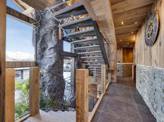 Experience luxury mountain living in this stunning chalet featuring a dramatic rock-inspired staircase and expansive windows with breathtaking snowy mountain views.
