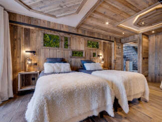 Experience rustic luxury in this charming bedroom, featuring two cozy beds adorned with plush white throws.