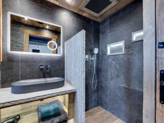 Experience modern luxury in this stunning bathroom featuring a sleek dark stone tile shower and a floating vanity with a contemporary basin sink.