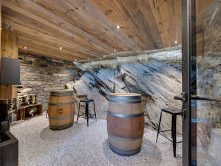 Experience rustic charm in this unique wine cellar, featuring natural stone walls and a striking rock face centerpiece.