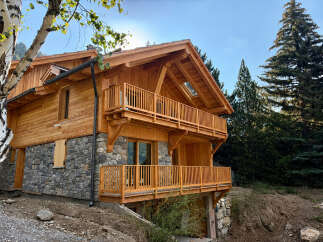 Experience luxury mountain living in this stunning wooden chalet, featuring a stone base and expansive balconies perfect for enjoying breathtaking alpine views.