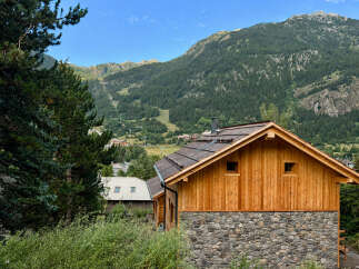 Experience mountain living in this charming wooden chalet, featuring a rustic stone base and a warm, inviting interior.