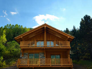 Experience luxury mountain living in this stunning wooden chalet, nestled amidst lush greenery and towering pine trees.