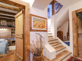 Experience rustic charm in this unique mountain retreat, featuring exposed wooden beams and a cozy bedroom with a plush blue bed.