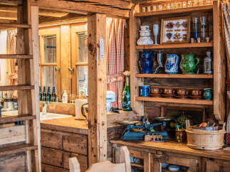Experience rustic charm in this cozy kitchen, featuring a charming wooden ladder and a well-stocked shelf display of decorative pitchers, cups, and jars.
