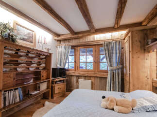 Experience rustic charm in this cozy bedroom featuring exposed wooden beams and a traditional plate rack display.