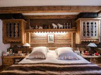 Experience rustic charm in this cozy bedroom, featuring a luxurious fur throw and plush pillows on a comfortable bed.