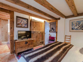 Experience rustic charm in this unique bedroom featuring exposed wooden beams and a cozy atmosphere.