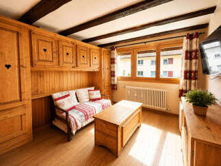 Experience rustic charm in this cozy living space featuring warm wooden cabinetry with heart cutouts and a comfortable daybed adorned with charming heart-patterned pillows.