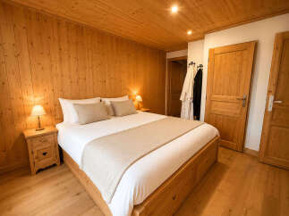 Experience rustic charm in this beautifully appointed bedroom, featuring warm wooden paneling on the walls and ceiling.