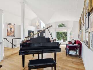 Experience luxury living in this grand foyer featuring a stunning black grand piano and a dramatic vaulted ceiling with a modern chandelier.
