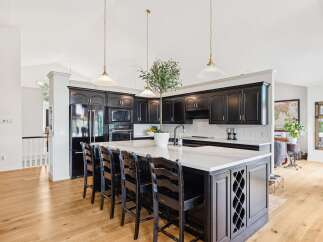 Experience luxury in this stunning kitchen featuring sleek black cabinetry and a spacious quartz-topped island perfect for entertaining.