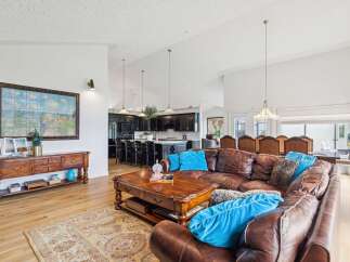 Experience luxurious open-concept living with this stunning home, featuring a spacious leather sectional and a large wooden coffee table perfect for gatherings.