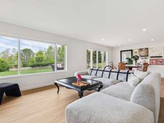 Experience seamless indoor-outdoor living in this beautifully appointed living room, featuring a large picture window that floods the space with natural light and offers serene views of the lush backyard.