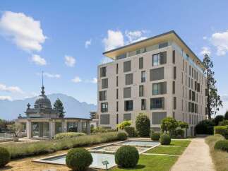 Discover modern luxury in this stunning property featuring a sleek, contemporary building with expansive windows and a rooftop terrace offering breathtaking mountain views.