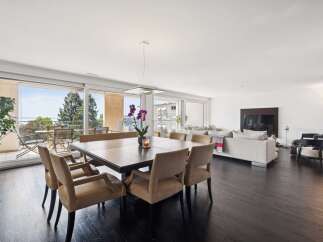 Experience luxurious living in this spacious open-concept dining and living area, featuring a large wooden dining table with plush chairs and a comfortable sectional sofa.