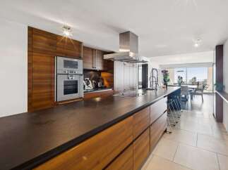 Experience modern luxury in this stunning kitchen featuring sleek, dark countertops and rich wood cabinetry.