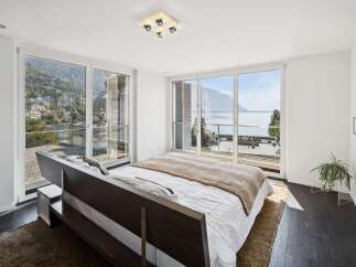 Experience breathtaking lake and mountain views from this luxurious bedroom, featuring expansive floor-to-ceiling windows that flood the space with natural light.