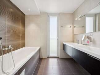 This modern bathroom features a sleek, freestanding bathtub with a textured brown tile accent wall, creating a spa-like ambiance.