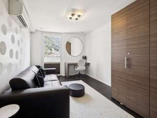 This modern living space features a sleek black leather sofa complemented by a stylish polka dot accent wall and a large window offering scenic views.
