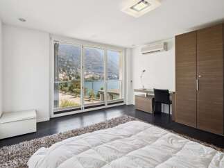 Experience breathtaking lake and mountain views from this modern bedroom, featuring a spacious walk-in closet and a dedicated workspace.