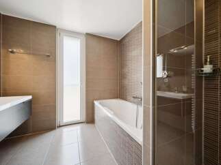 Experience modern luxury in this stunning bathroom, featuring a sleek vanity, a deep soaking tub, and a separate glass-enclosed shower.