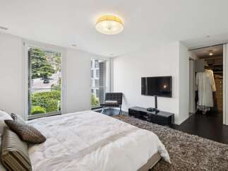 Experience luxury living in this spacious master bedroom, featuring a king-sized bed adorned with plush linens and decorative pillows.