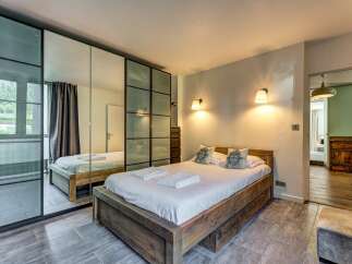 Experience comfort and style in this beautifully appointed bedroom, featuring a spacious wooden bed and elegant wall-mounted lamps.